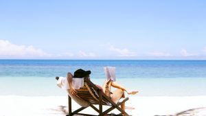 Woman reading book in deckchair on the beach